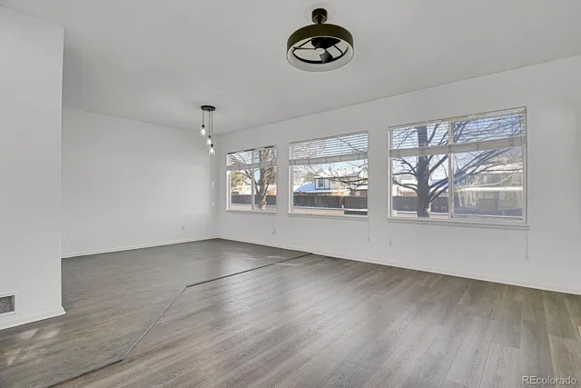 a view of an empty room with window and wooden floor