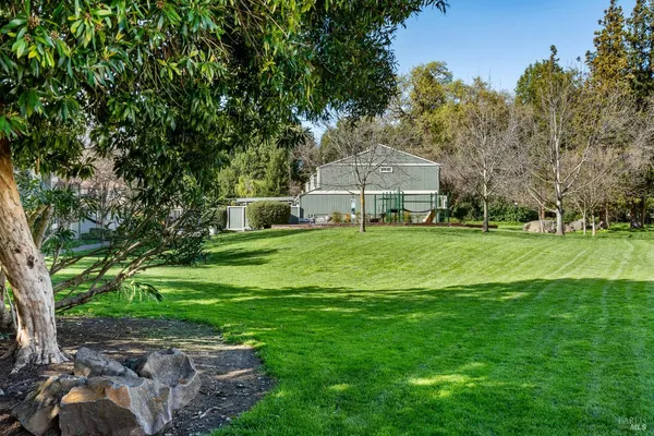 a view of a house with a big yard and large trees