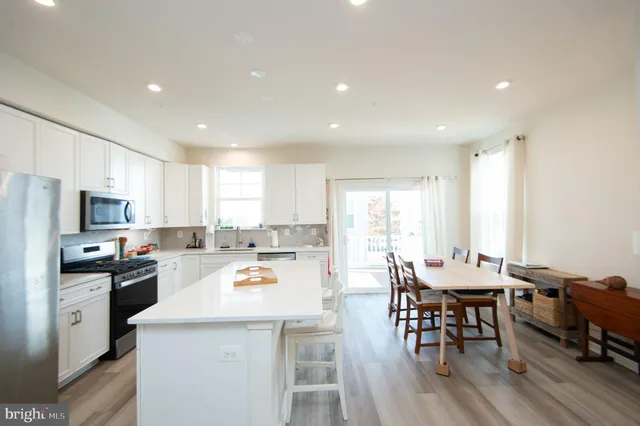 a kitchen with a dining table chairs stove refrigerator and cabinets