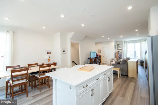 a large kitchen with sink a refrigerator and chairs