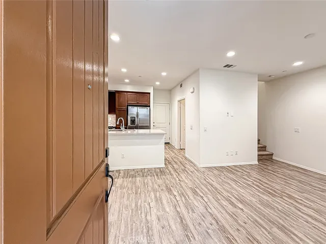a view of a kitchen with kitchen island wooden floor center island and stainless steel appliances