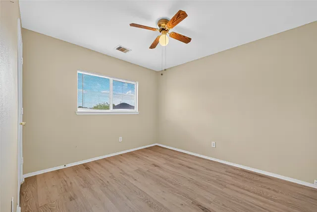 an empty room with wooden floor and ceiling fan