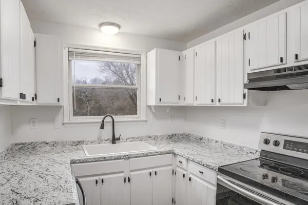 a kitchen with granite countertop a sink stove and cabinets