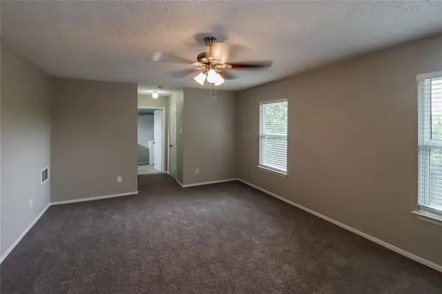 an empty room with windows and fan