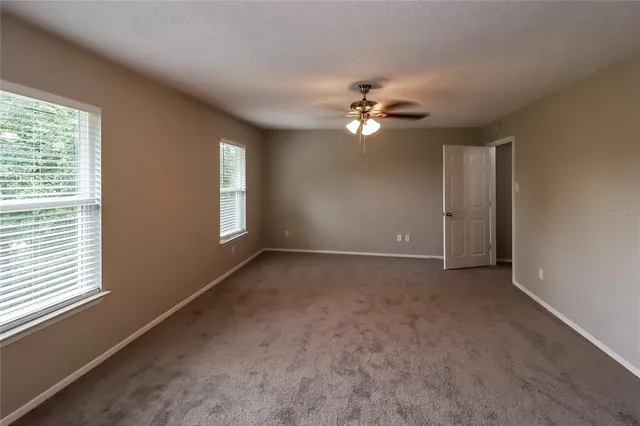 an empty room with windows and fan