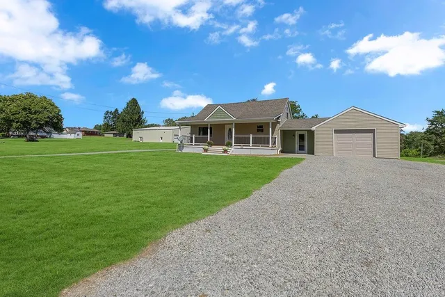 a front view of a house with a garden and trees