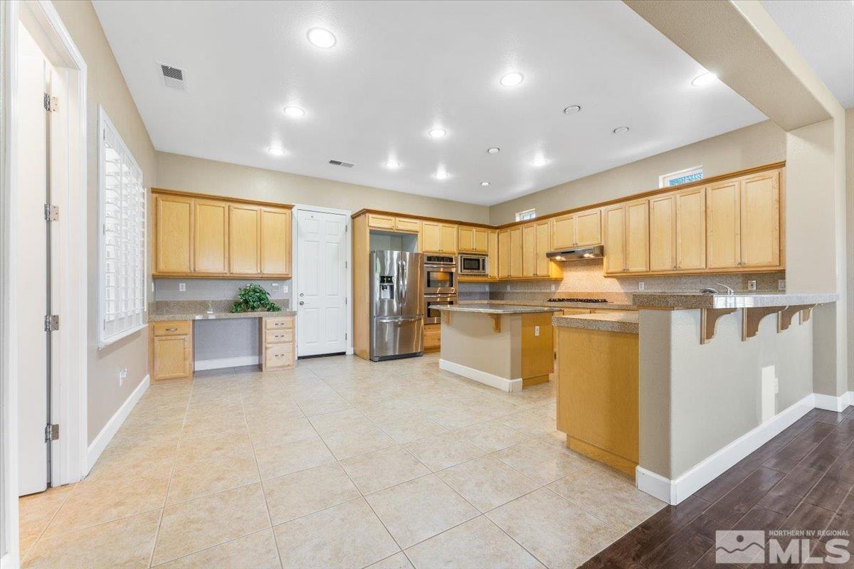 10145 Burghley Lane Reno, NV 89521 - Photo 11 of 31 a large white kitchen with lots of counter space cabinets and stainless steel appliances
