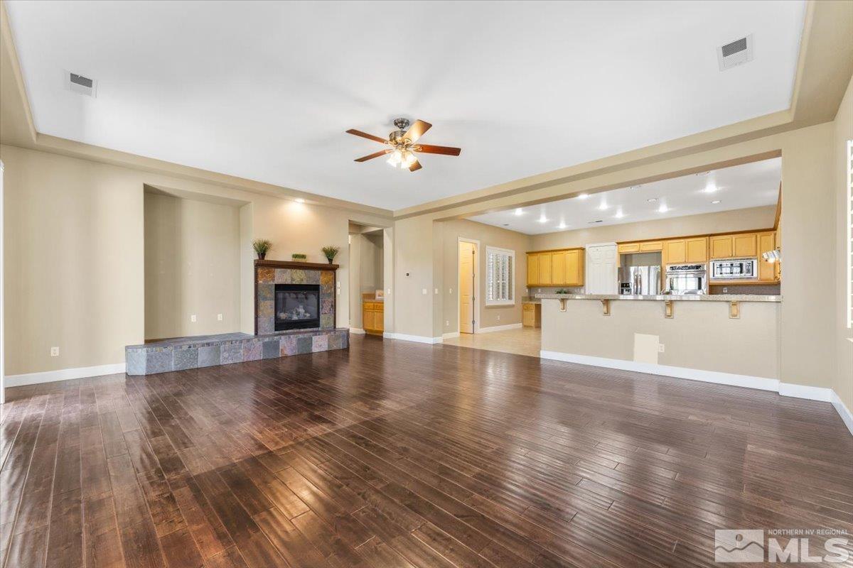 10145 Burghley Lane Reno, NV 89521 - Photo 8 of 31 an empty room with wooden floor and a kitchen