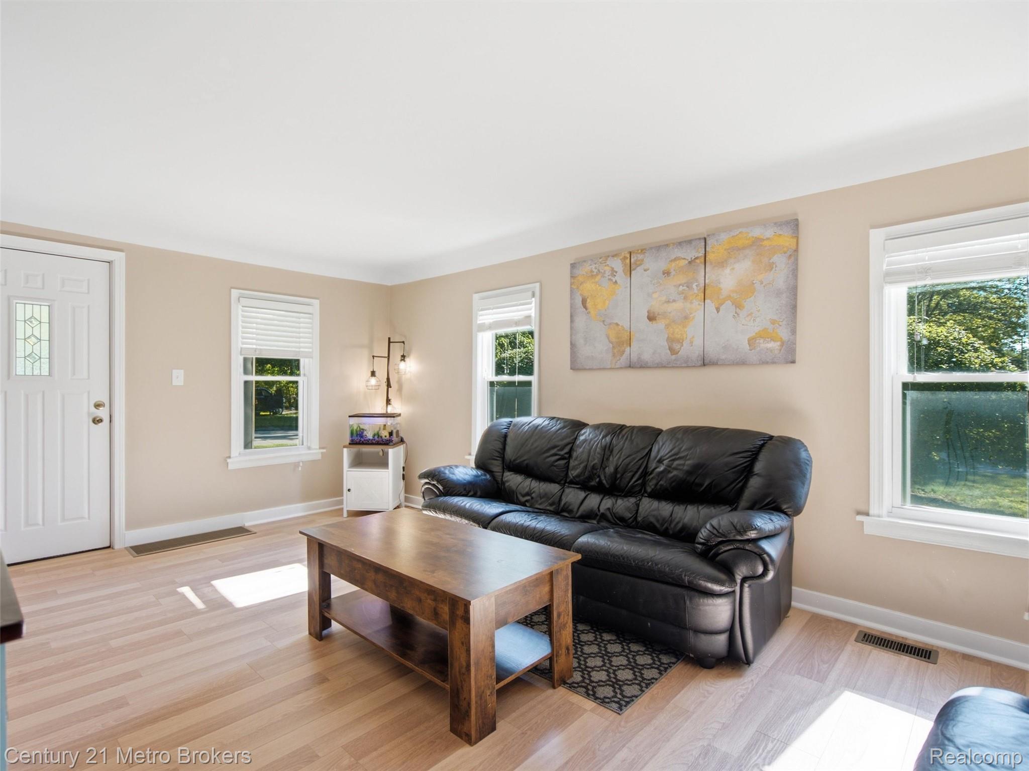 301 Field Road Clio, MI 48420 - Photo 6 of 29 Bright living area featuring light wood-finish flooring, neutral wall paint, and multiple windows with white trim