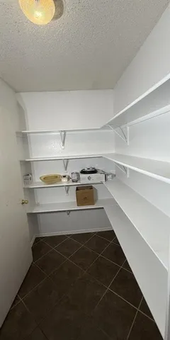 a view of an empty room with wooden floor and a ceiling fan