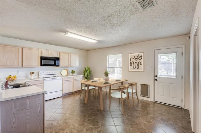 a kitchen with stainless steel appliances granite countertop a stove top oven a sink a dining table and chairs with wooden floor