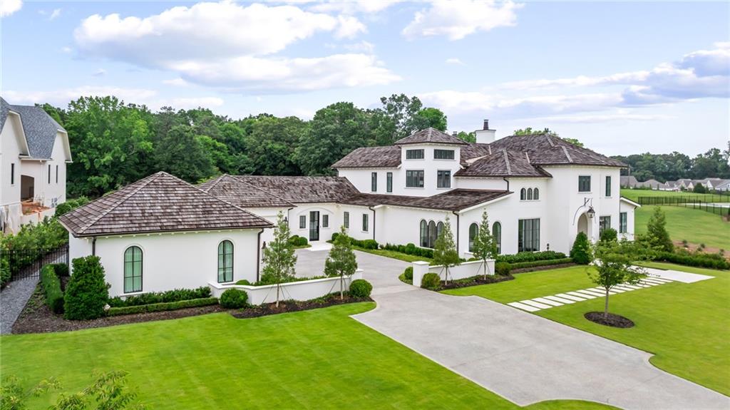 a front view of a house with a garden and lake view