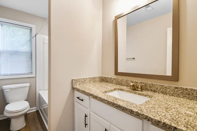 a bathroom with a granite countertop sink toilet and shower