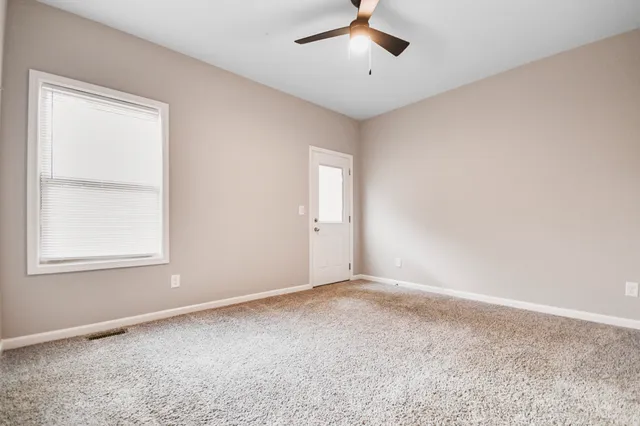 an empty room with a window and a fan