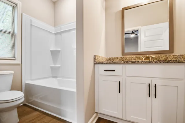 a bathroom with a granite countertop sink toilet and shower