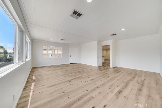 a view of empty room with wooden floor and windows