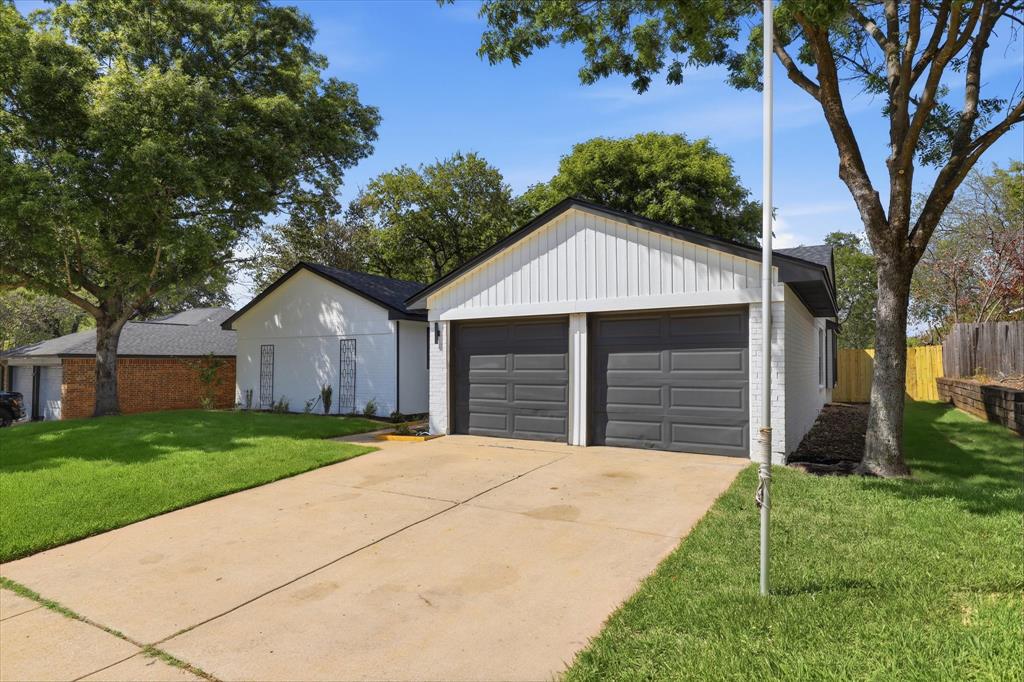 3405 Mill Ridge Street Bedford, TX 76021 - Photo 31 of 32 Two-car garage with dark paneled doors, light vertical siding, and a dark shingle roof
