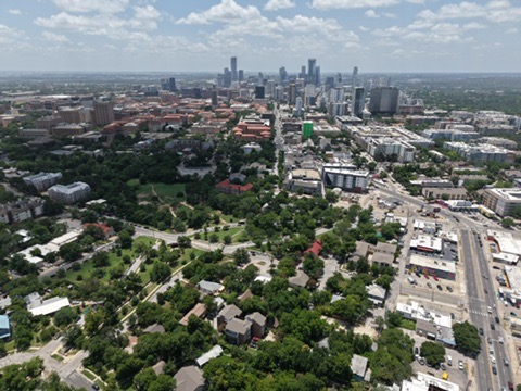 3011 Fruth Street, Unit 101 Austin, TX 78705 - Photo 14 of 14 A panoramic aerial perspective showcases an urban landscape meeting a verdant tree canopy under a vast sky.