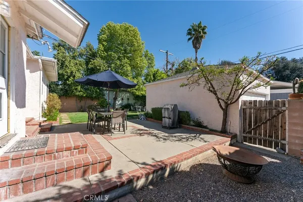 a view of a patio with table and chairs under an umbrella with potted plants