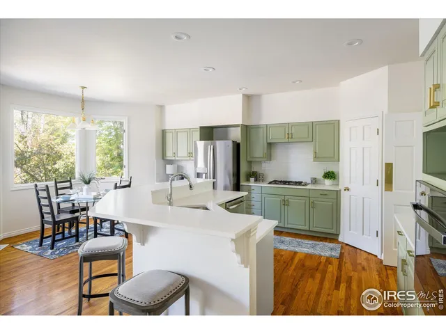 a kitchen with stainless steel appliances kitchen island granite countertop a table chairs and a refrigerator