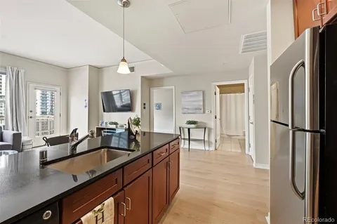 a kitchen with stainless steel appliances kitchen island granite countertop a refrigerator a stove a sink a dining table and chairs with wooden floor