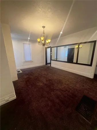 a view of an empty room with chandelier fan and wooden floor
