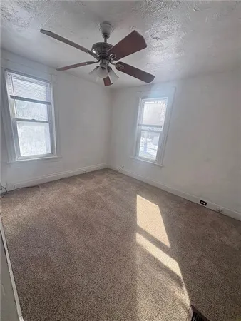 an empty room with windows and fan