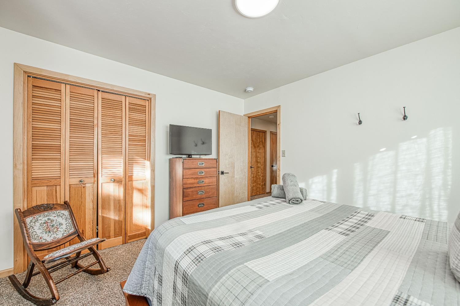55578 Cordwood Road Shaver Lake, CA 93664 - Photo 18 of 59 a bedroom with a bed and chair next to a large window