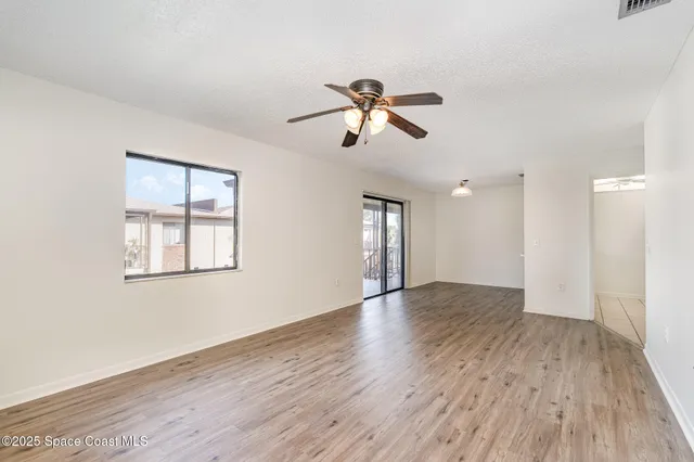 a view of empty room with wooden floor and fan