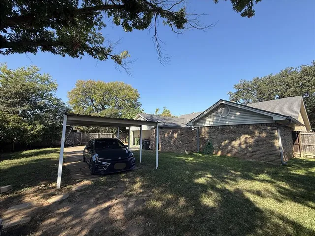 a view of backyard with wooden fence and a large tree