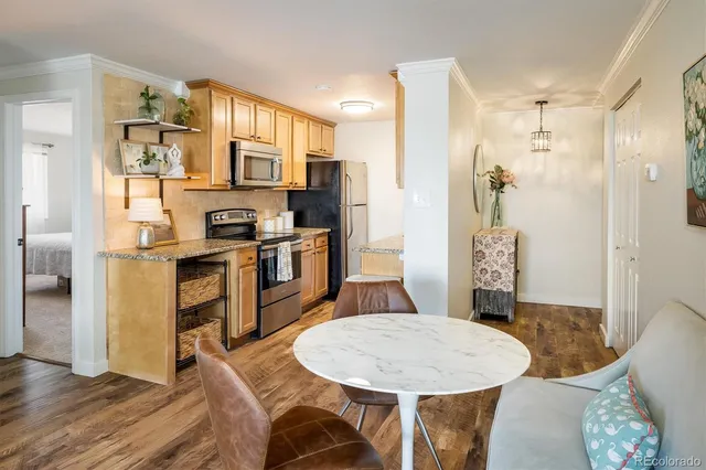 a kitchen with stainless steel appliances a dining table chairs and refrigerator