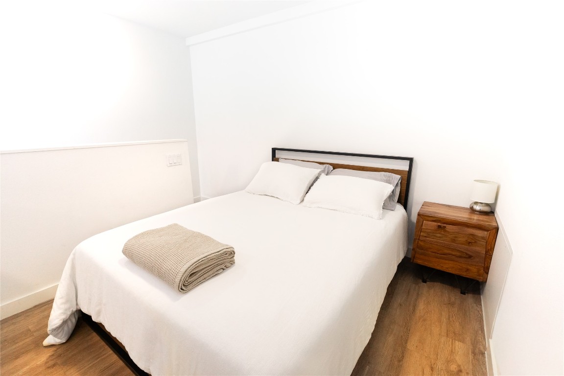 49 Navasota Street, Unit 209 Austin, TX 78702 - Photo 13 of 32 a bedroom with a bed and a night stand