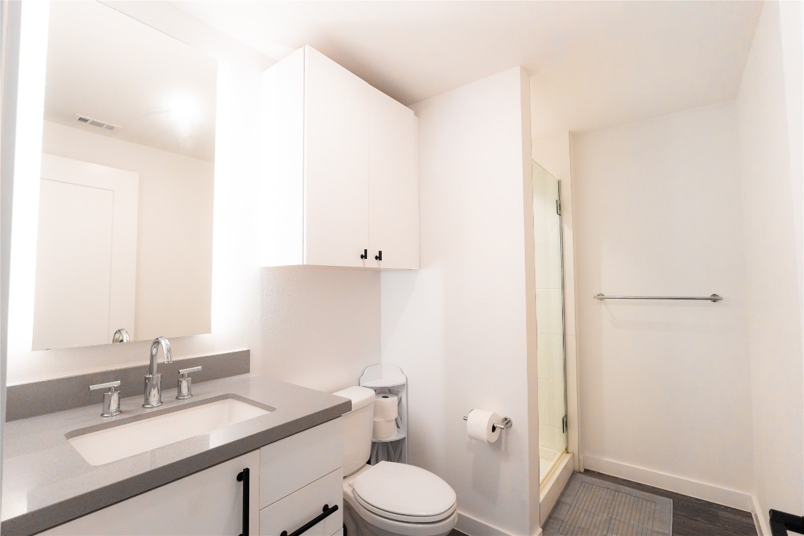 49 Navasota Street, Unit 209 Austin, TX 78702 - Photo 10 of 32 a bathroom with a granite countertop sink mirror vanity and toilet