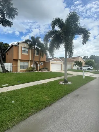 a view of a house with a big yard and large trees