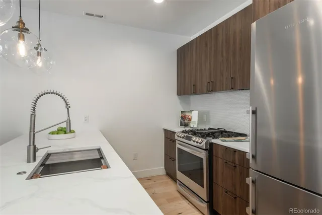 a kitchen with granite countertop a stove a sink and a refrigerator
