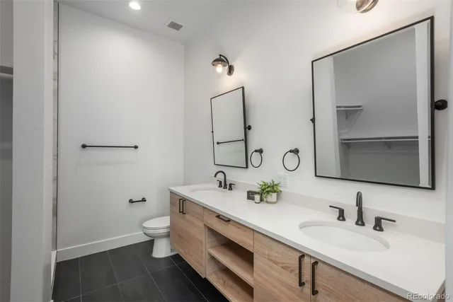a bathroom with a double vanity sink toilet and mirror