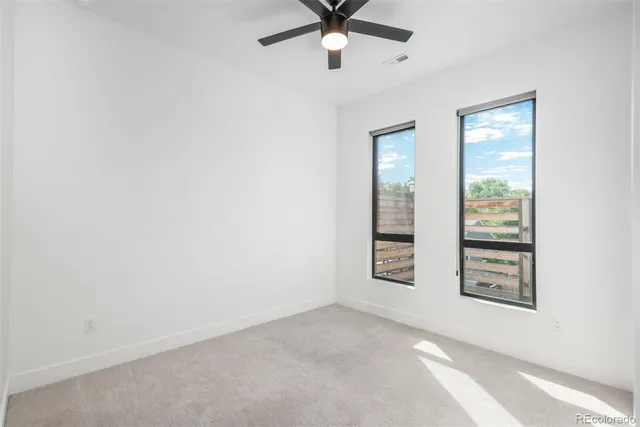 an empty room with windows and fan