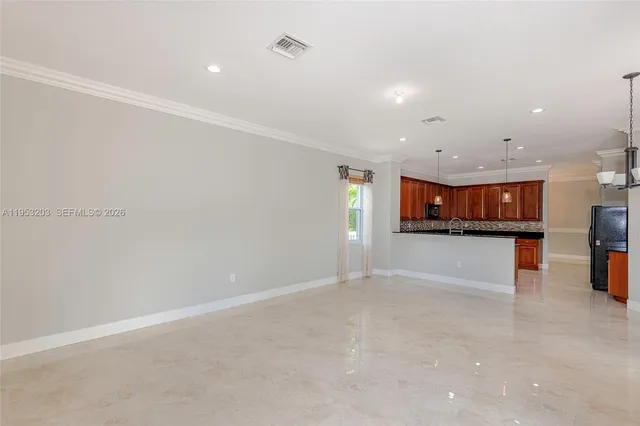 an empty room with kitchen view and a window