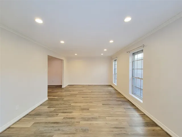a view of an empty room with wooden floor and kitchen