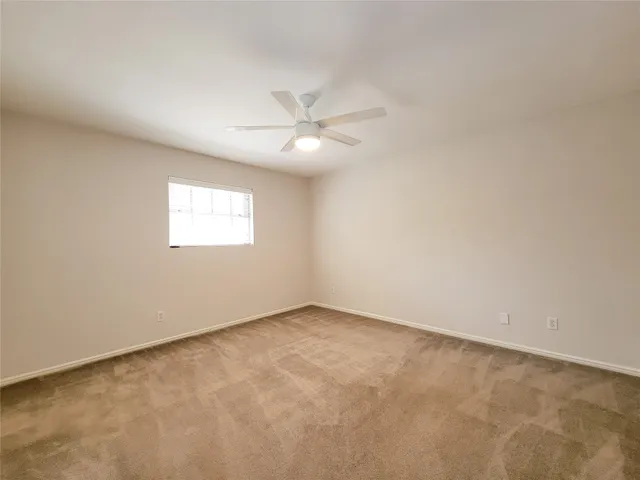 an empty room with a window and a ceiling fan
