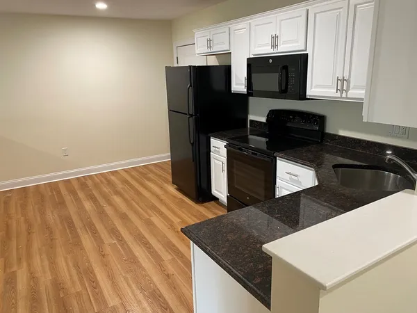 a kitchen with a sink dishwasher a refrigerator and cabinets with wooden floor