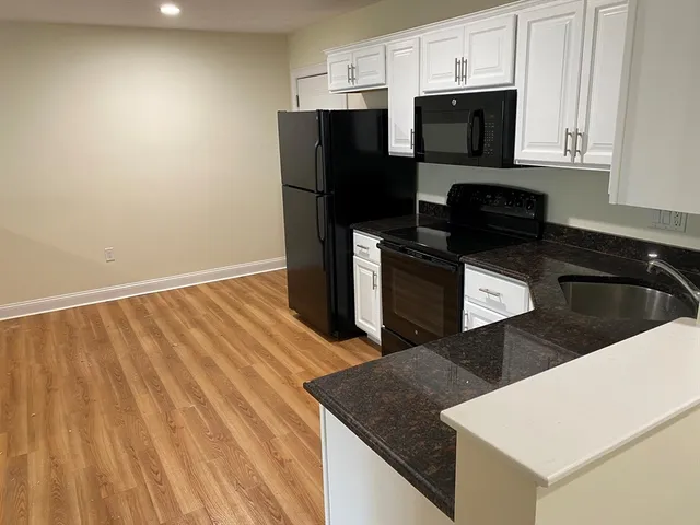 a kitchen with a sink dishwasher a refrigerator and cabinets with wooden floor