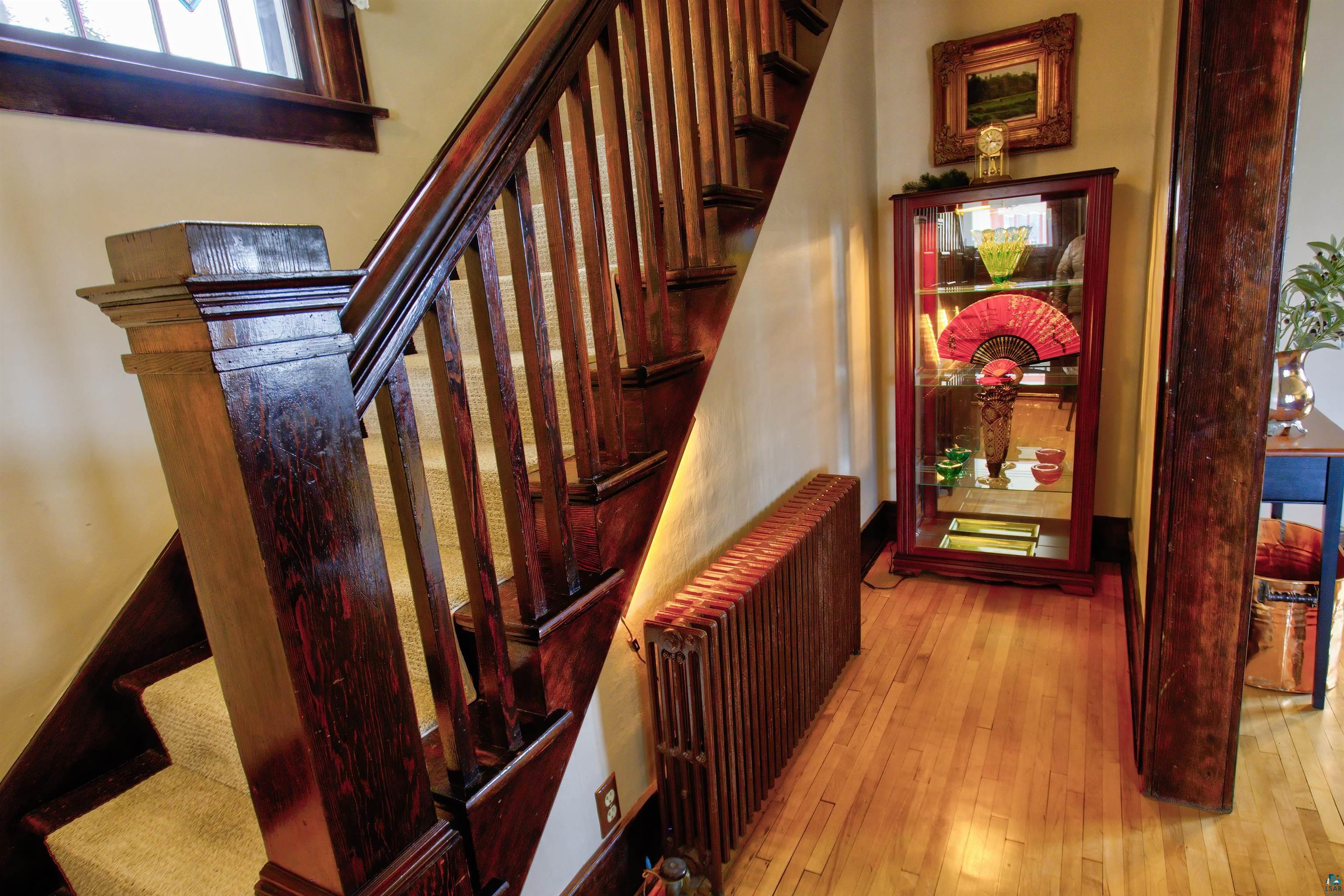 24 East Conan Street Ely, MN 55731 - Photo 4 of 27 Hardwood flooring extends from the entryway, complemented by a substantial wood staircase featuring carpeted treads