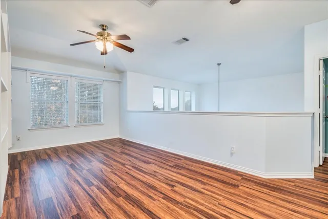 a view of empty room with wooden floor and fan