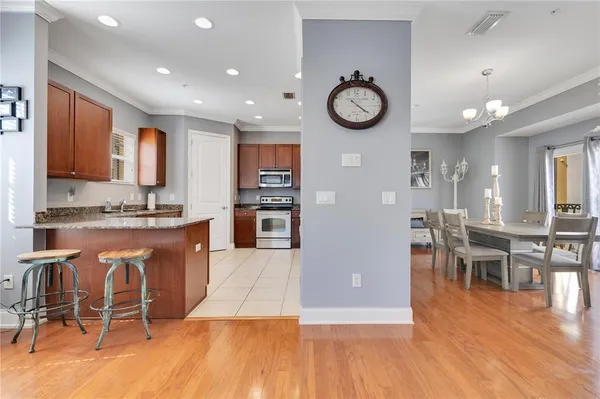 a view of a kitchen with kitchen island granite countertop wooden floor and stainless steel appliances