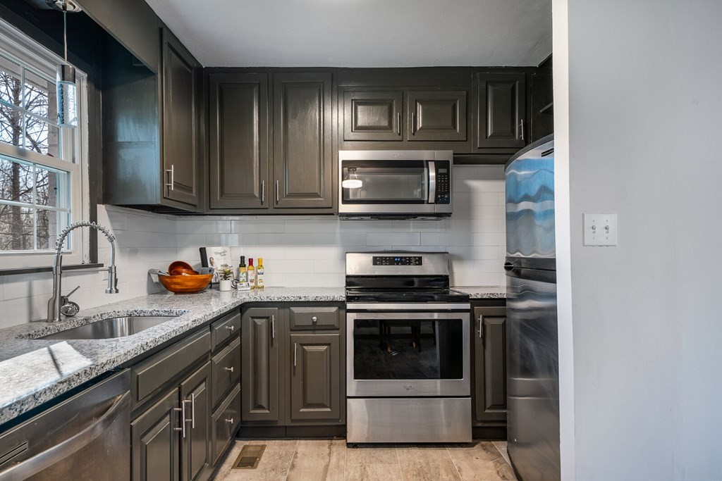329 Sunny Point Road Baxter, TN 38544 - Photo 13 of 25 a kitchen with stainless steel appliances granite countertop a stove a microwave and a sink