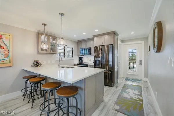 a kitchen with stainless steel appliances granite countertop a dining table chairs refrigerator and sink