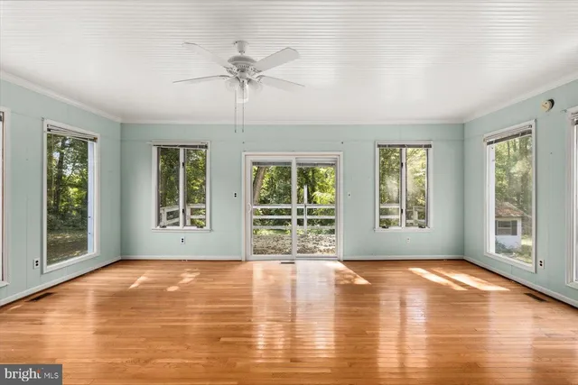a view of an empty room with window and wooden floor