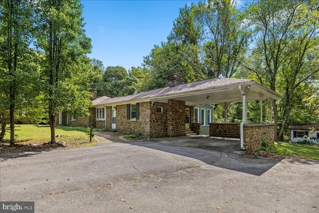 a view of a house with large trees and wooden fence
