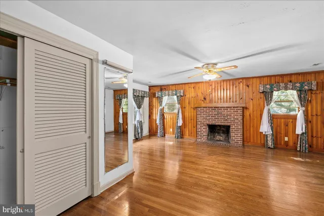 a view of an empty room with wooden floor fireplace and a window